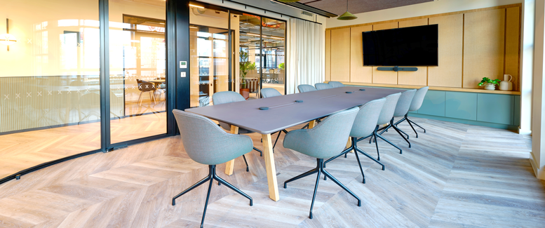 Mødelokale indrettet med konferencebord og glaspartier
