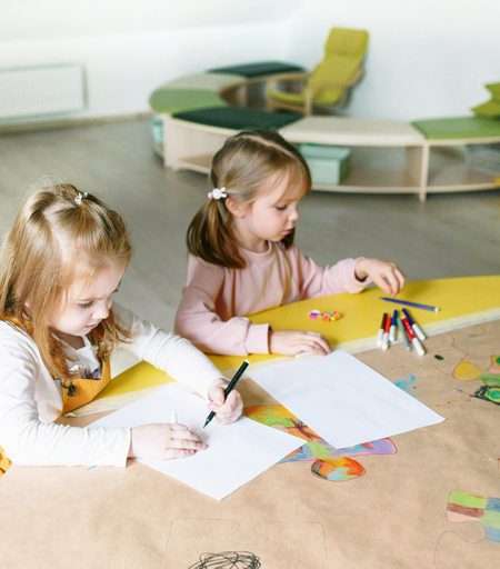 2 piger i en børnehave der tegner i et indrettet lokale